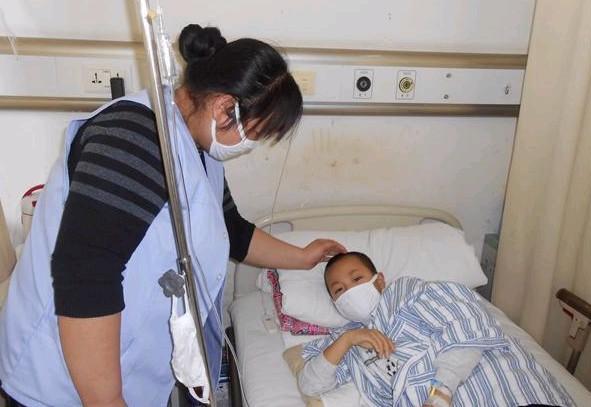在医院上疗时孩子妈妈细心的照顾孩子,摸摸孩子的额头,看看体温有所升高没。
