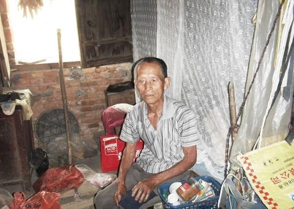陈振民老人做在床上,没有像样的生活用品,居住环境非常的艰苦。