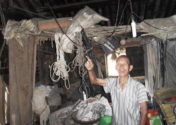 陈振民老人站在家楼上,瓦片泥土房子,下雨天漏雨,居住的是危房。