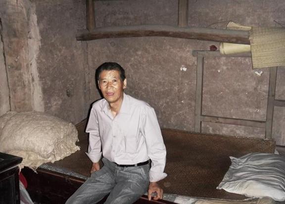 盛昌兴坐在自己的床上,生活家具陈旧,生活非常的艰苦