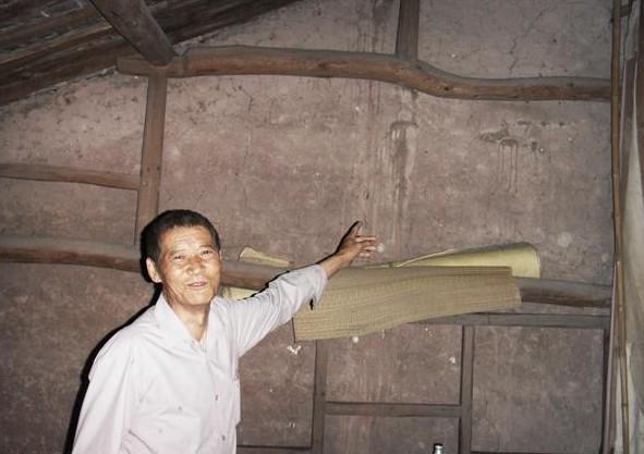 盛昌兴站在家楼上,木头结构的房子,墙壁上有下雨漏雨留下的痕迹非常明显。