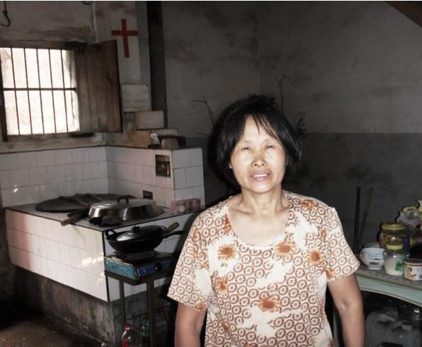 蒋桂风站在家里,平时为了省点钱,家里用土灶烧饭,土灶破旧,生活条件困难。