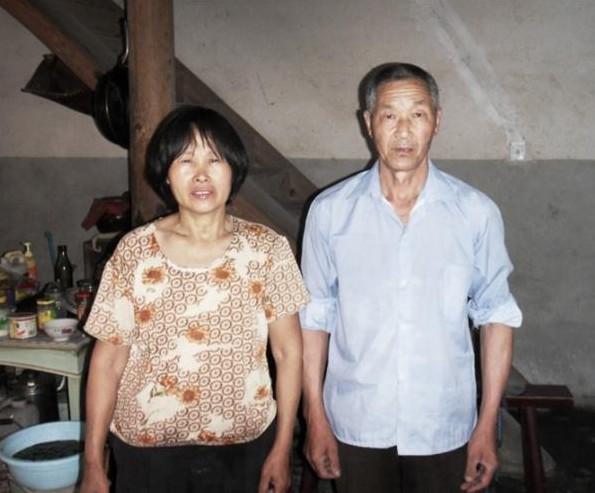 蒋桂风和丈夫站在家里,丈夫年纪大腰椎病体弱多病,家里没有固定收入,生活困难。