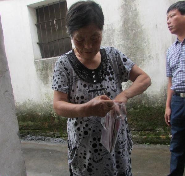 吴筱贞的母亲将得到的捐款仔细的放进小袋子里面