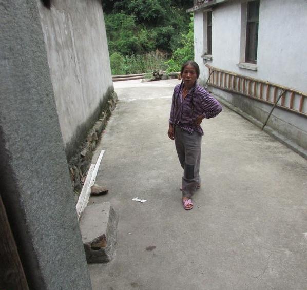 吴根巧身上的衣服很破烂,还打着补丁,穿着很破旧的拖鞋