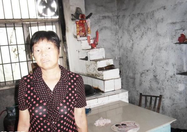 张玲凤站在家里,平时为了省点钱,家里用土灶烧饭,生活条件困难。
