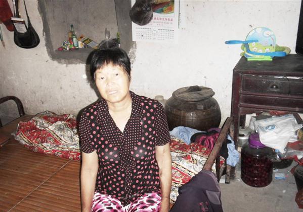 张玲凤坐在自己的床上,生活家具陈旧,生活非常的艰苦。