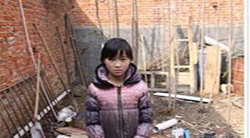 受助人杨彤站在自家墙角