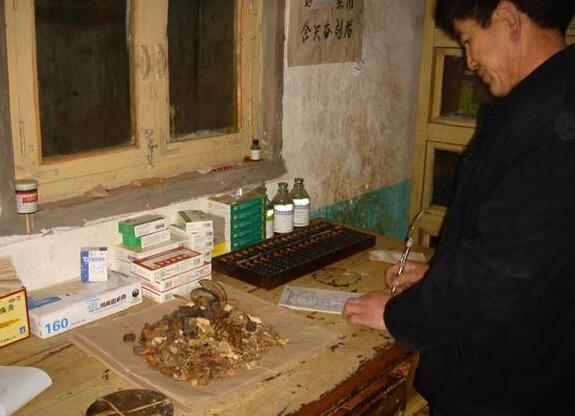 贫困山区卫生所大夫正在给冯三科开药方的照片