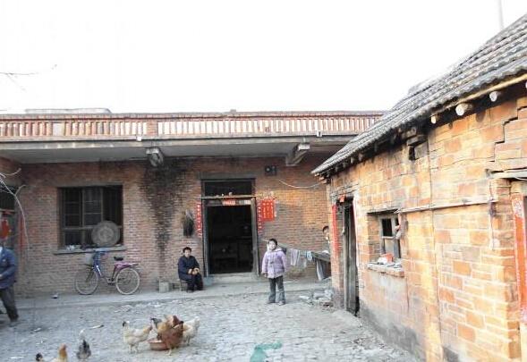 王荣歌一家四口人居住的几间砖瓦房的外景照,家里养了一些鸡子,鸡子下蛋拿去卖钱贴补家用