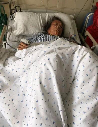 老人躺在床上看着志愿者的到来,但是已经无力坐起。