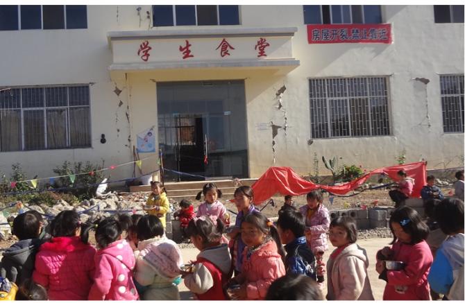 鲁甸县龙头山镇沙坝第二小学地震受灾严重,学校周围现在还到处是废墟,学校食堂房屋开裂严重,孩子们坚持上学,在食堂外就餐