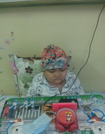 为了减少化疗的痛楚,爸爸用手机放动画片给孩子看。