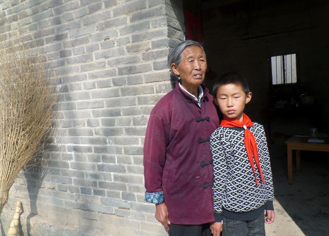 老人和孙子站在门口盼望着……