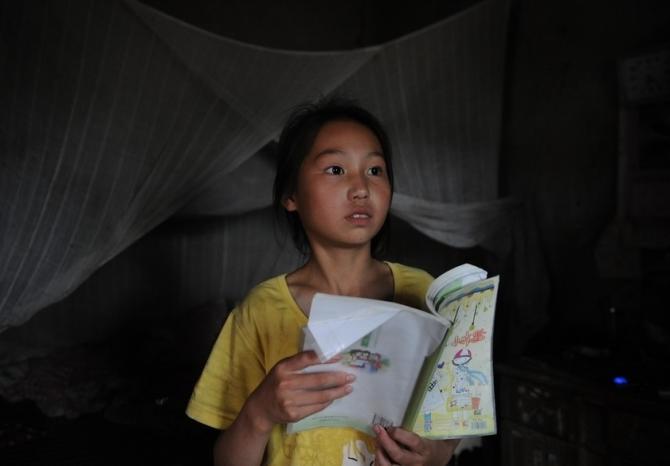 孤独的童年---爱学习的听障小姑娘在灯光昏暗的屋子里读书